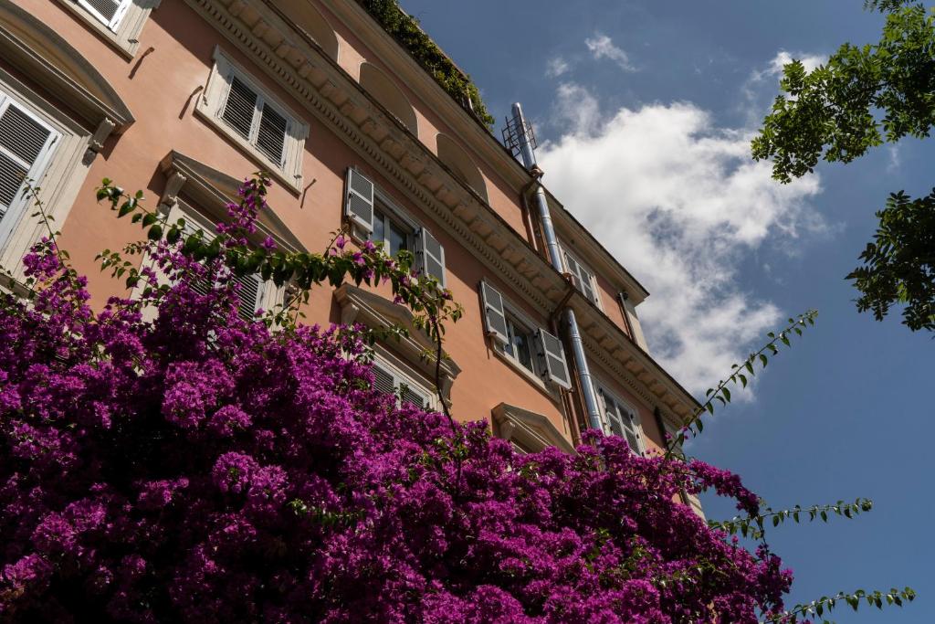 罗马罗马瓦尔德斯酒店的一座在前面布满紫色花的建筑