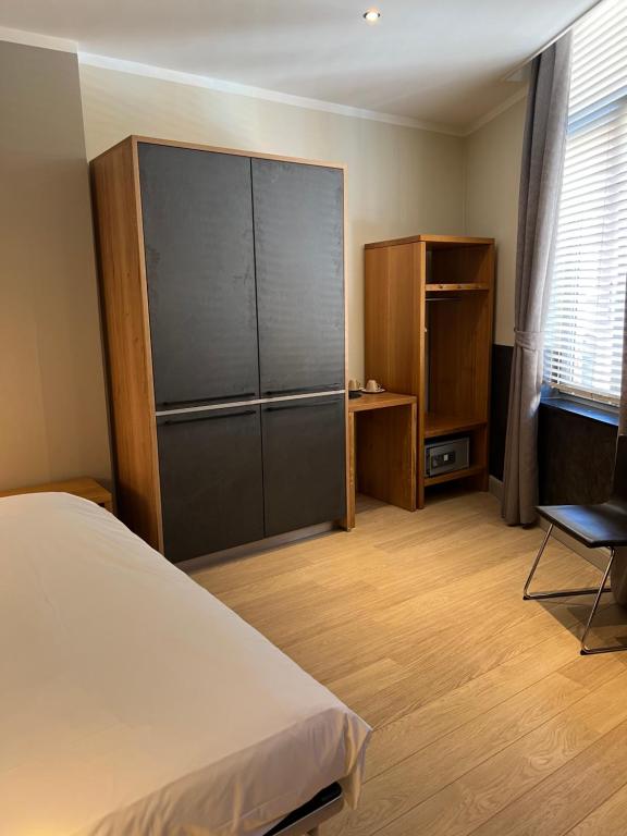 鲁汶博德郝行酒店的一间卧室配有一张床、一个橱柜和一把椅子