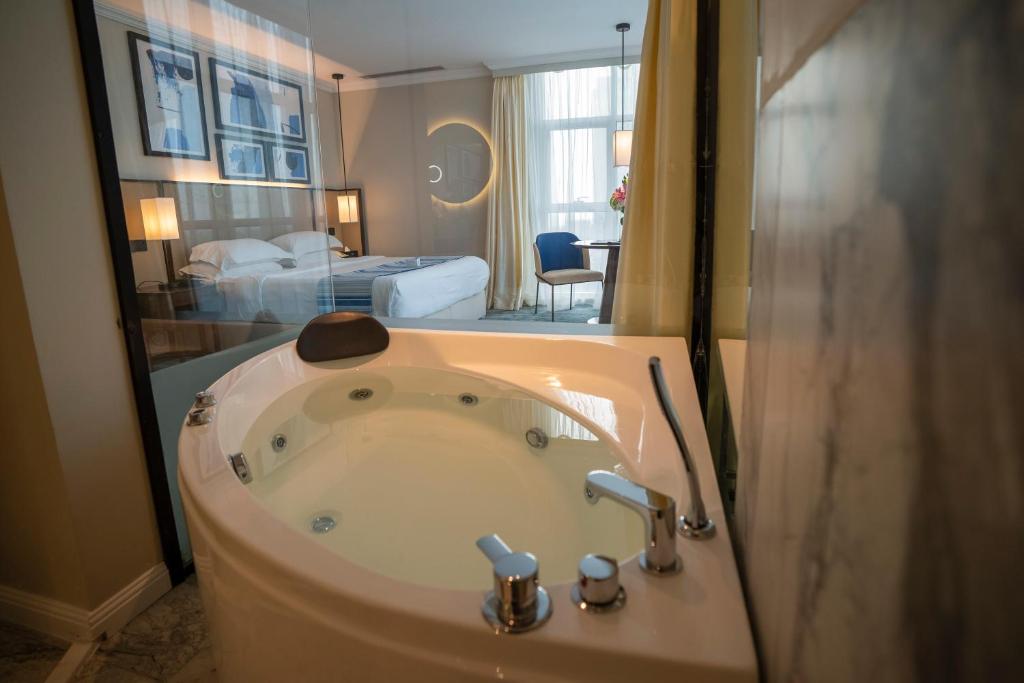 吉达Prime Al Corniche Hotel的一间带浴缸、一张床和一间卧室的浴室