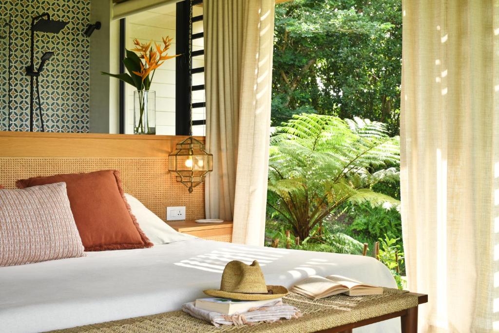 沙马雷勒ChamGaia off-grid eco-villa的一张带窗子桌子上帽子的床