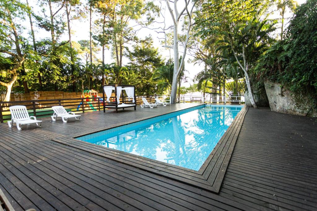 弗洛里亚诺波利斯Cabanas Praia Mole Florianopolis的一个带椅子和树木的木制甲板上的游泳池