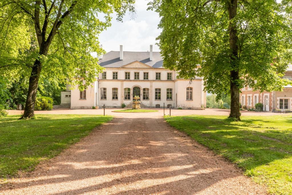 CharmeilChâteau de Charmeil- Vichy chambres d'hôtes的通往一个树木繁茂的白色房子的车道