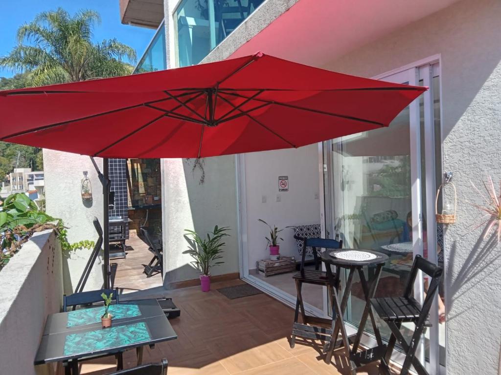 阿蒂巴亚Hospedagem Sol Nascente的露台上的红色遮阳伞,配有桌椅