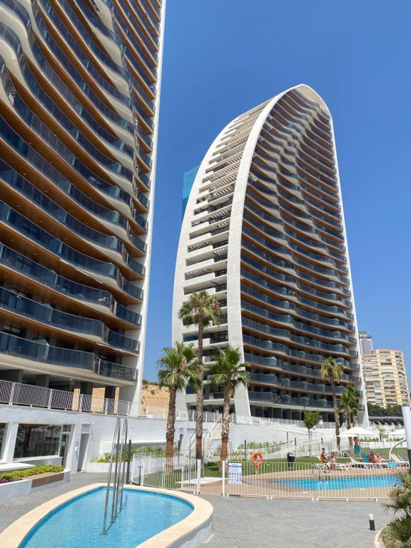 贝尼多姆SUNSET WAVES blue sky apartment的两栋高大的建筑,种植了棕榈树,设有游泳池