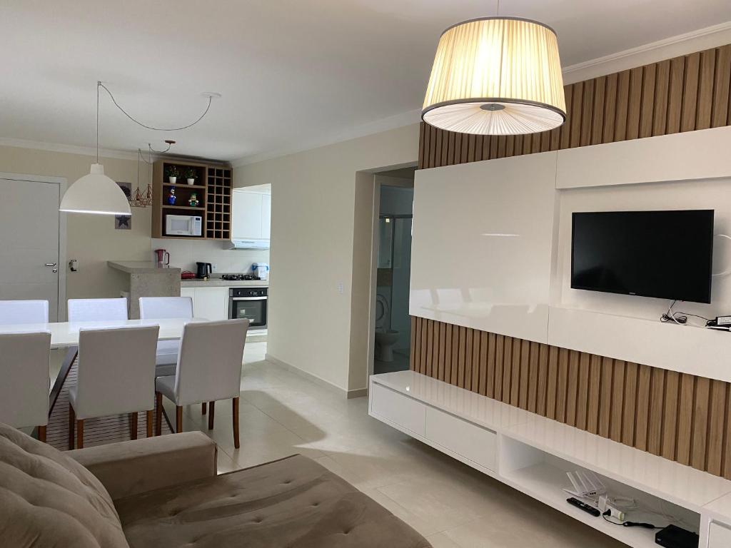 邦比尼亚斯Apartamento Novo Praia de Bombas的客厅以及带电视和桌子的厨房。