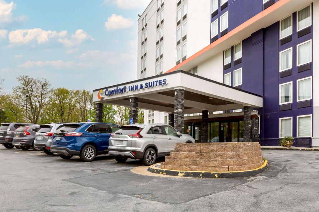 亚历山德里亚Comfort Inn & Suites Alexandria West的停车场,停车场的汽车停在大楼前