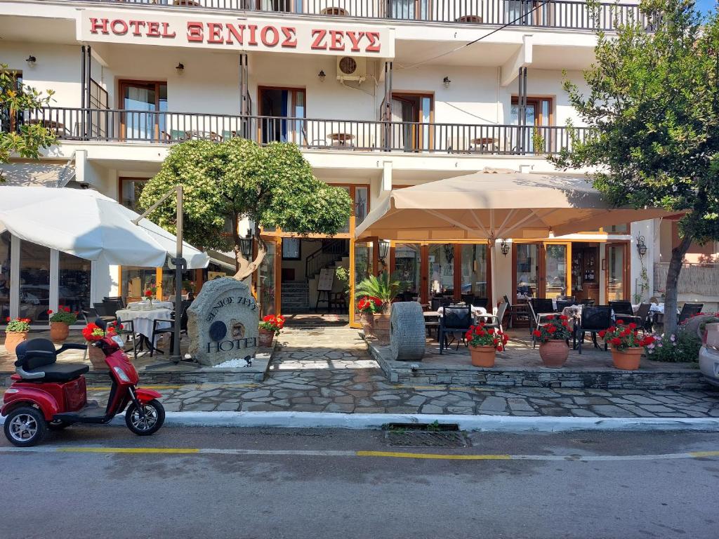 欧拉努波利斯Xenios Zeus的停在酒店前的摩托车,配有桌子和遮阳伞