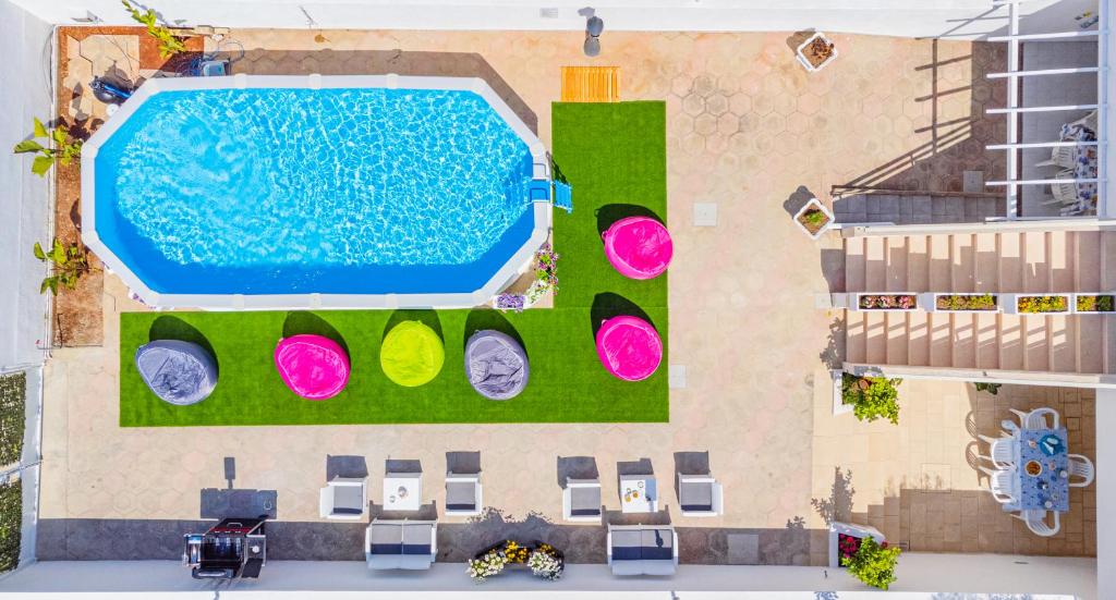 莱乌卡Chiara & Giulia Apartments by HDSalento的享有带绿草和粉红色的游泳池的顶部景致