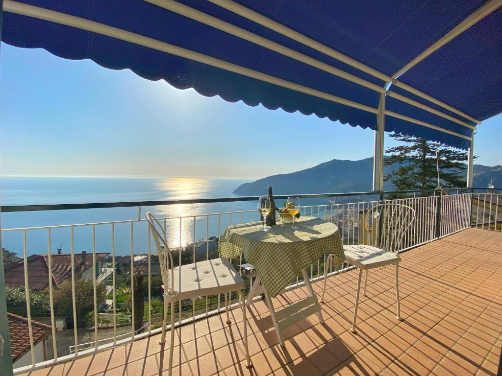 莫内利亚Appartamento Moneglia的阳台配有桌子、两把椅子和一把遮阳伞。