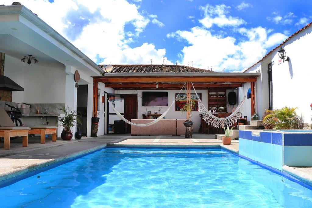比尔卡班巴Hostel las Palmas的房屋设有游泳池和带吊床的庭院