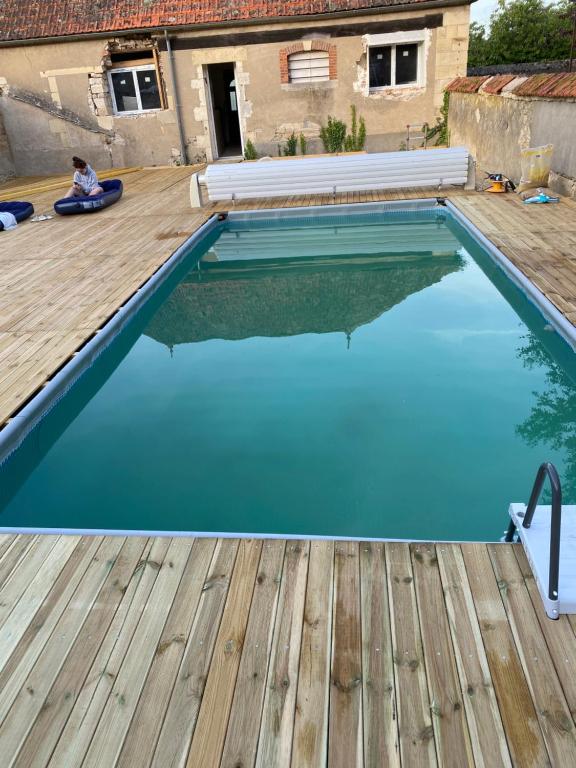 圣皮埃尔－勒穆捷LE CHARME DE ST PIERRE的一个带木甲板和蓝色海水的游泳池
