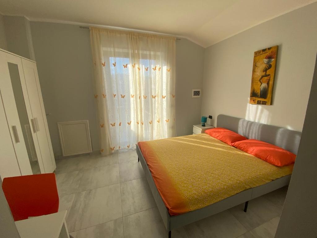 贝内文托B&B Santa Colomba的一间卧室配有带橙色床单的床和窗户。