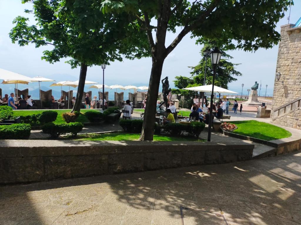 圣马力诺贝拉维斯塔酒店的坐在公园里的人,有树和遮阳伞