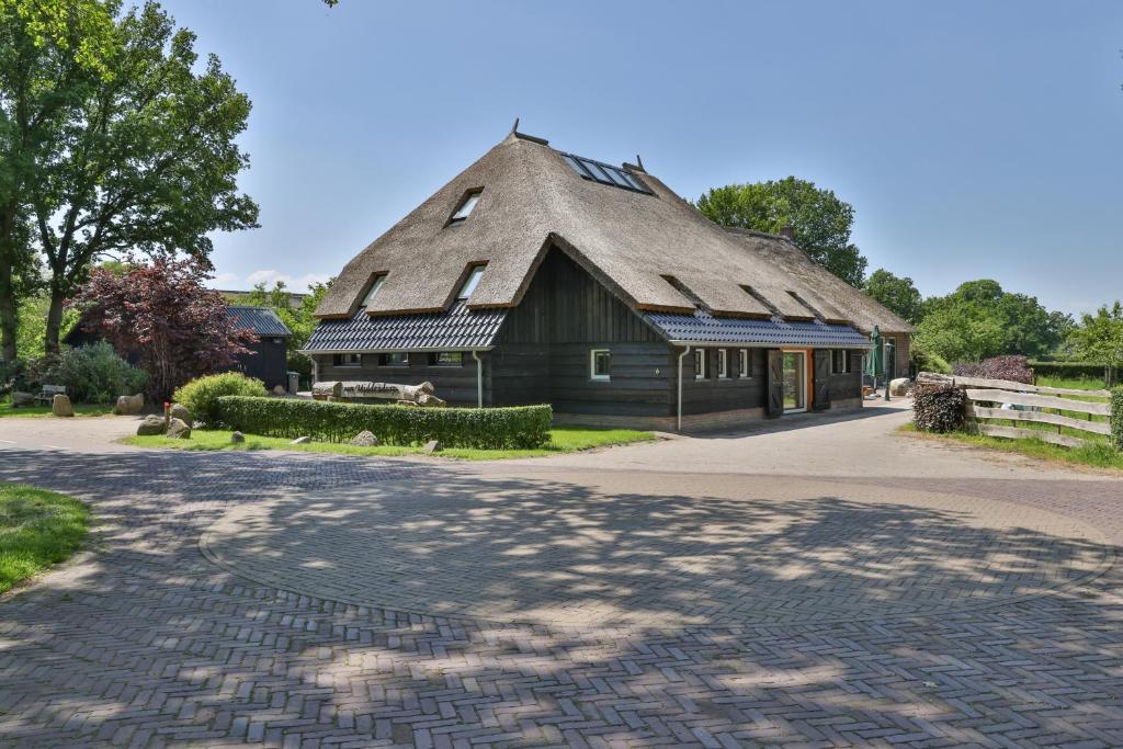 Ansenerve Middendorp的一座带茅草屋顶的建筑,前面有一条鹅卵石街道