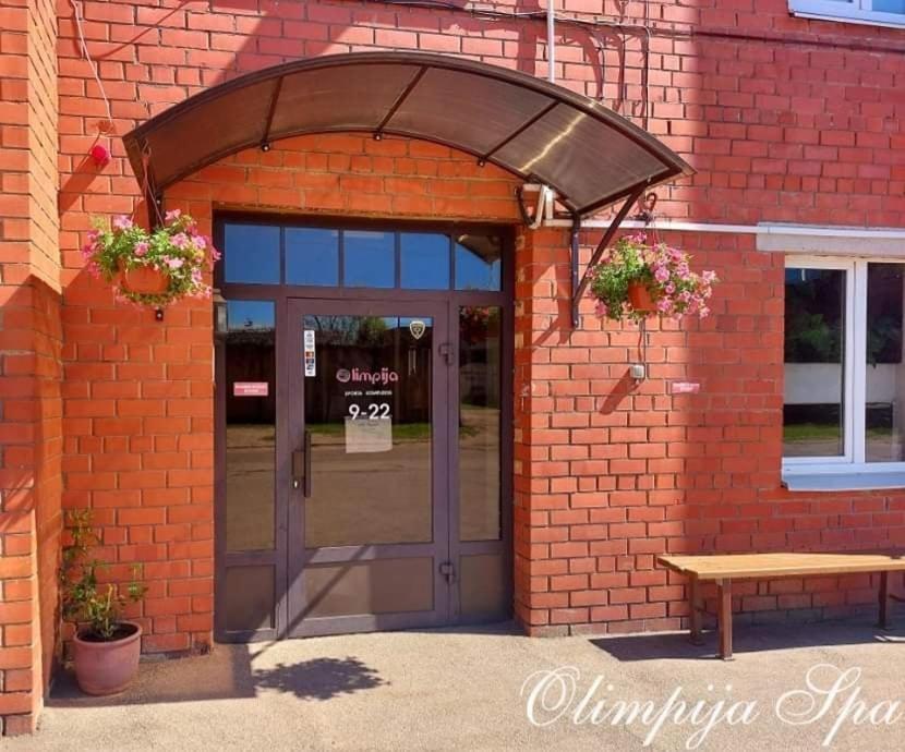 陶格夫匹尔斯Olimpija Hotel & SPA的砖砌建筑的入口,有门和长凳