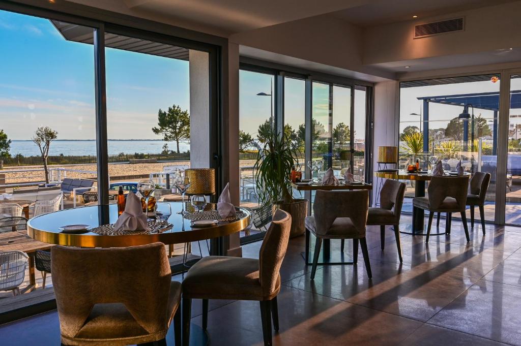 卡纳克Le Diana Hôtel & Spa NUXE的一间带桌椅的海景餐厅