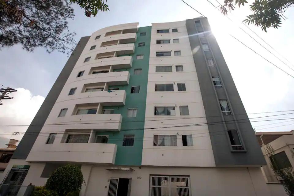 科恰班巴Departamento bien ubicado con 2 habitaciones con camas dobles的一座高大的公寓楼,绿白