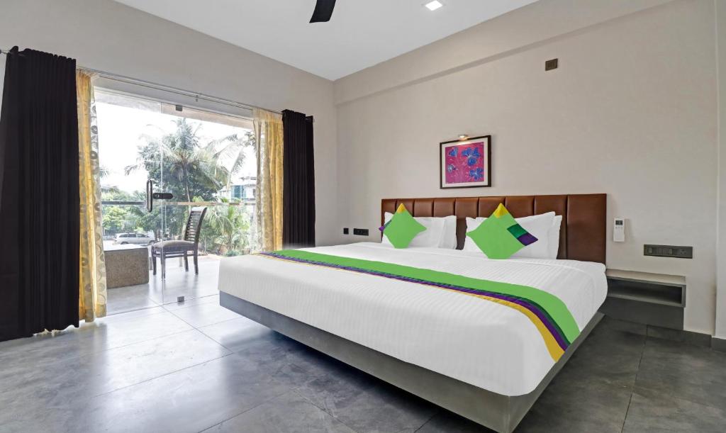 科钦Treebo Trend Grand Vistara Airport Suites的一间卧室设有一张大床和一个大窗户