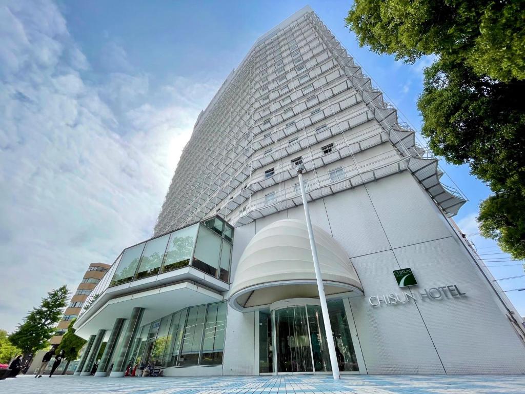 横滨横滨伊势佐木町岐山酒店(Chisun Hotel Yokohama Isezakicho) 的一座高大的白色建筑,拥有玻璃幕墙
