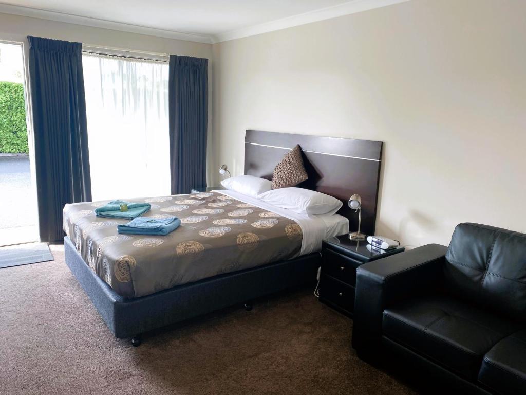 TerangDalvue Motel的一间卧室配有一张床、一张沙发和一把椅子