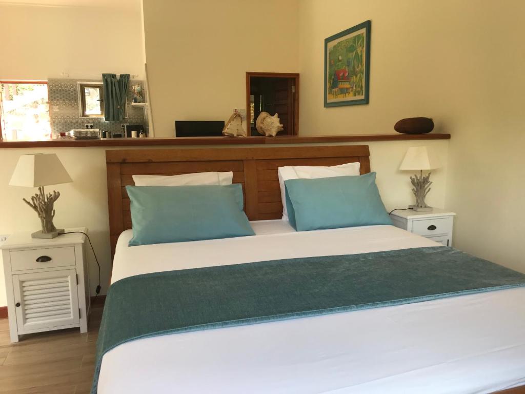 马埃岛贝拉扎尔区Rock and Palm Lodge Self catering appartment的卧室配有带蓝色枕头的大型白色床