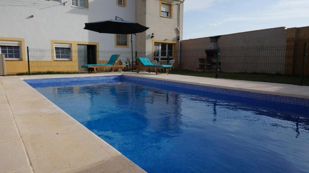 阿卡斯CUENCALOFT LAS LAGUNAS DE ARCAS的蓝色游泳池设有两把椅子和一把遮阳伞