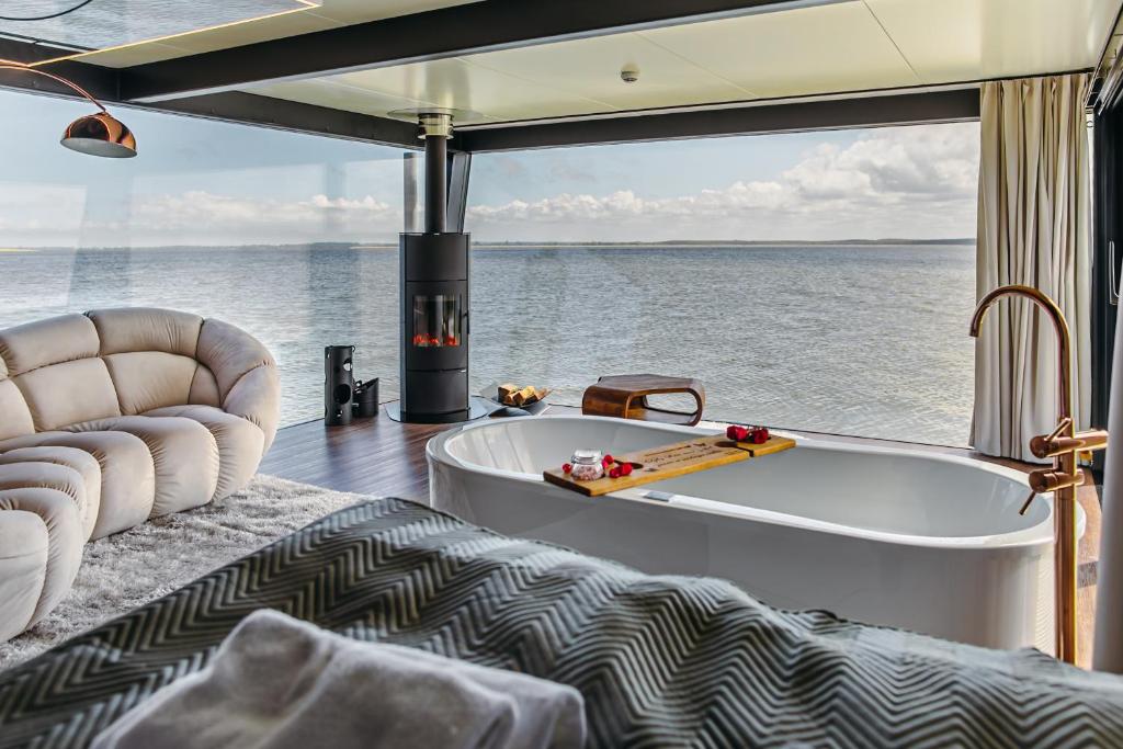 梅尔诺Domki na wodzie - Grand HT Houseboats - with sauna, jacuzzi and massage chair的客房享有水景,设有浴缸。