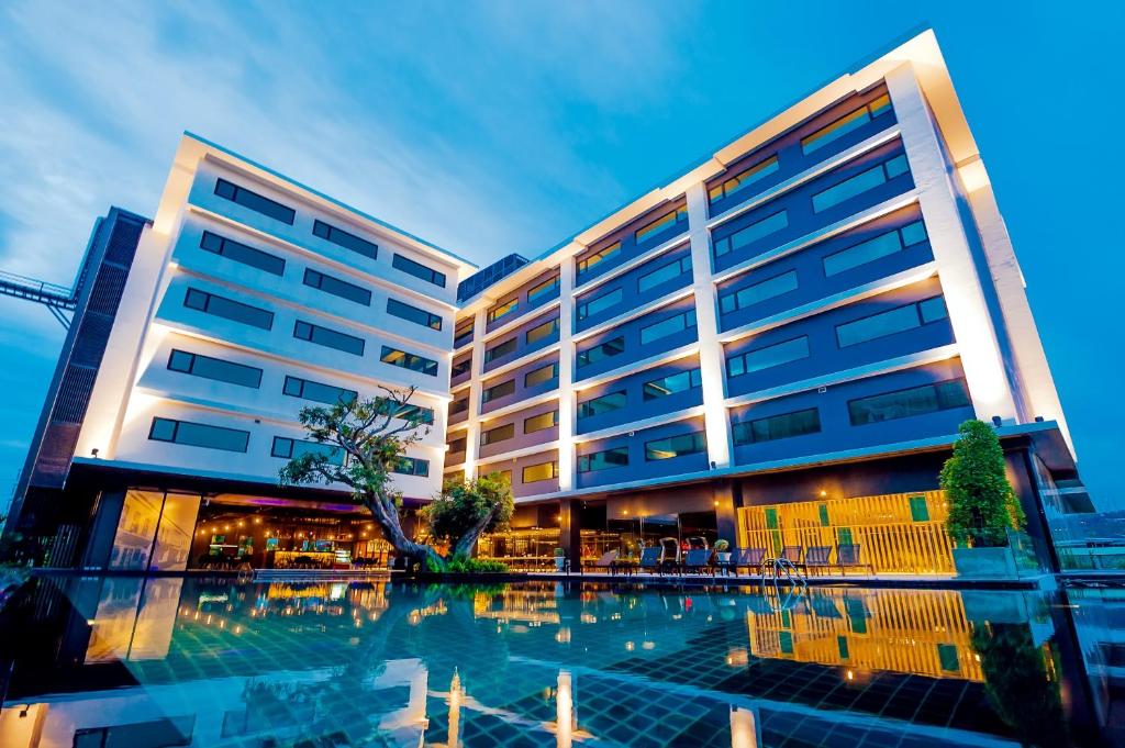 普吉镇DARA Hotel - SHA Plus的一座大型建筑,前面设有一个游泳池