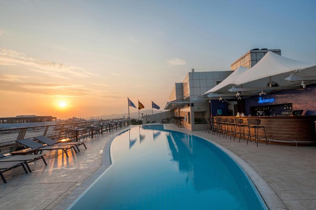雅典雅典美利亚酒店的一座享有日落美景的建筑的顶部游泳池
