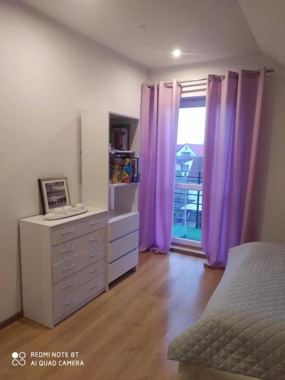 科乌切沃Apartament u Małgosi的一间卧室配有紫色窗帘、梳妆台和窗户