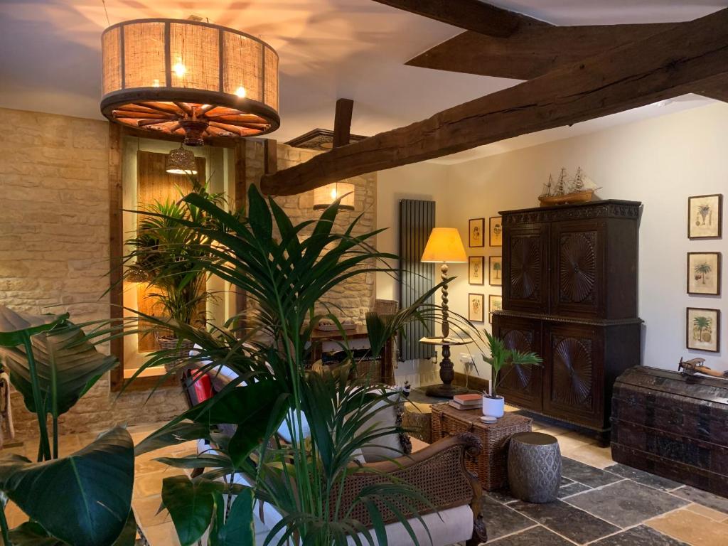 奇平诺顿Dovecote Cotswold Cottages的一间拥有大型植物和天花板的客厅