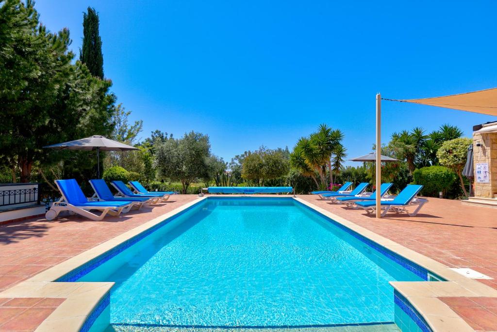 库克里亚4 bedroom Villa Kellia with private pool, Aphrodite Hills Resort的一个带蓝色椅子和遮阳伞的游泳池