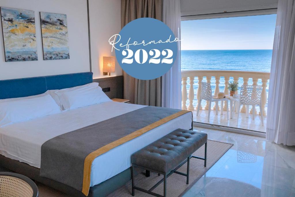 锡切斯URH锡切斯海滩酒店的一间卧室配有一张床,享有海景