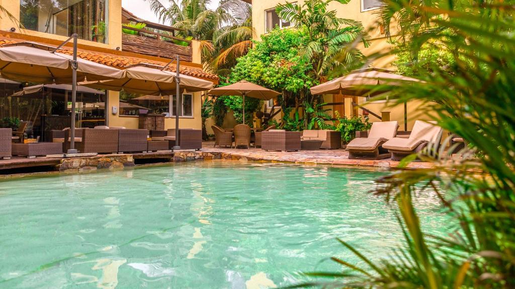 阿克拉拉维拉精品酒店的一座带椅子和遮阳伞的游泳池位于一座建筑旁边