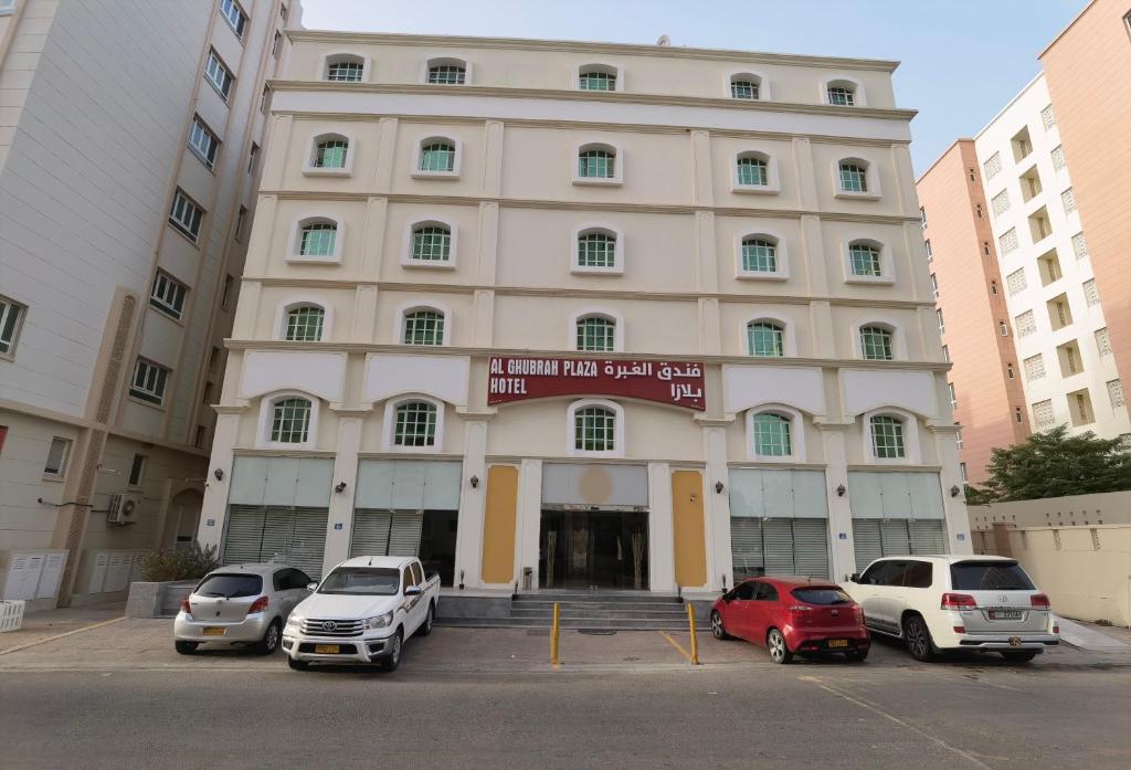 马斯喀特Al Ghubrah Plaza Hotel的停车场内停放汽车的大型建筑