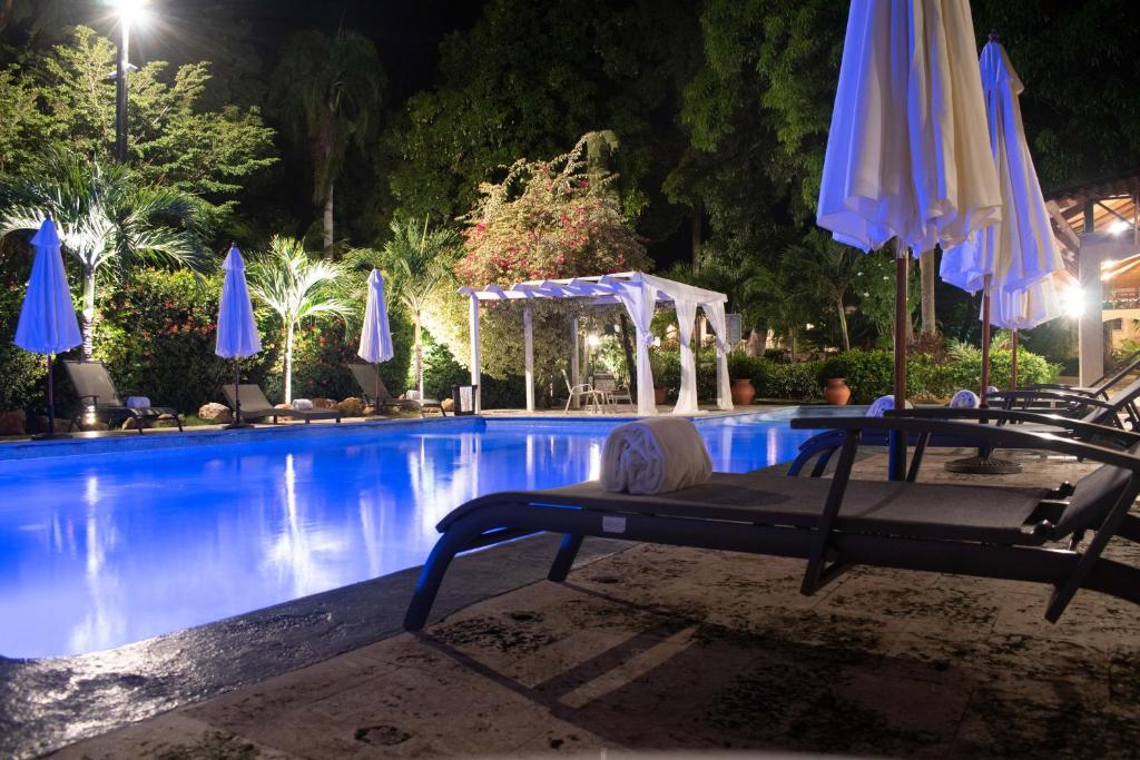海地角卡纳别墅酒店的一个带遮阳伞和桌椅的游泳池