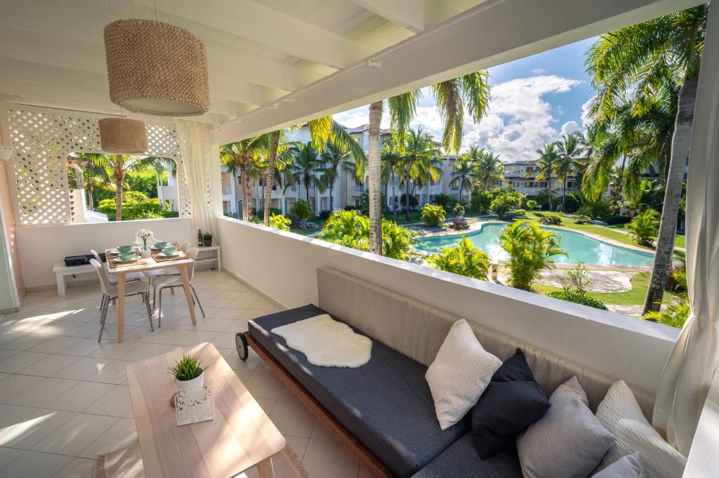 巴亚希贝Family Dominicus Apartment - Bayahibe的带沙发的客厅,享有游泳池的景色