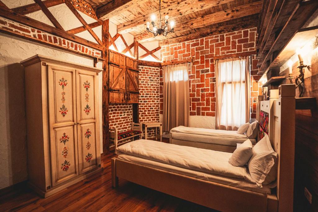 伊内乌Conacul Sfântul Sava Brancovici的一间卧室设有两张床和砖墙