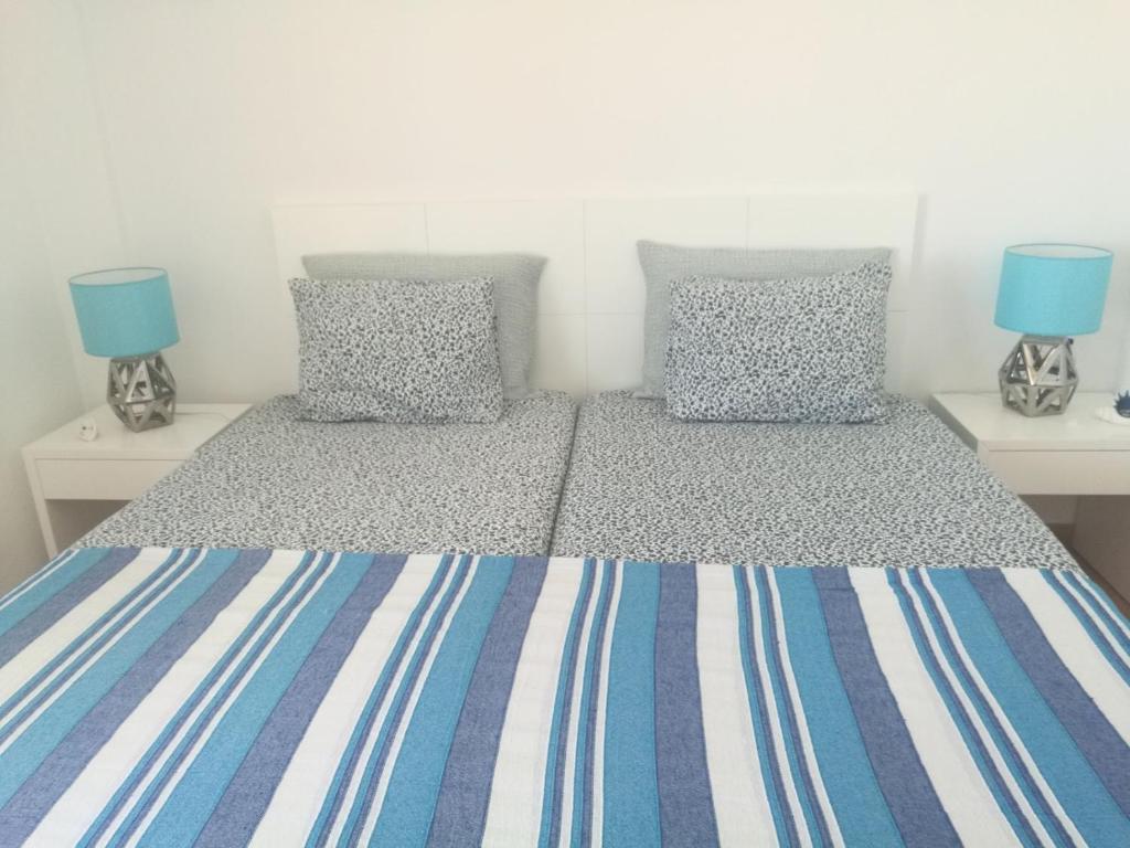 蒙蒂戈杜Casa ao Mar的一间卧室配有两张单人床和蓝色枕头。