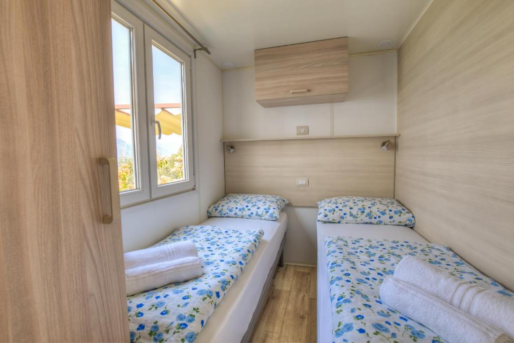 布伦佐内堡Agricampeggio Relax Maxicaravan的带2扇窗户的小客房内的2张床