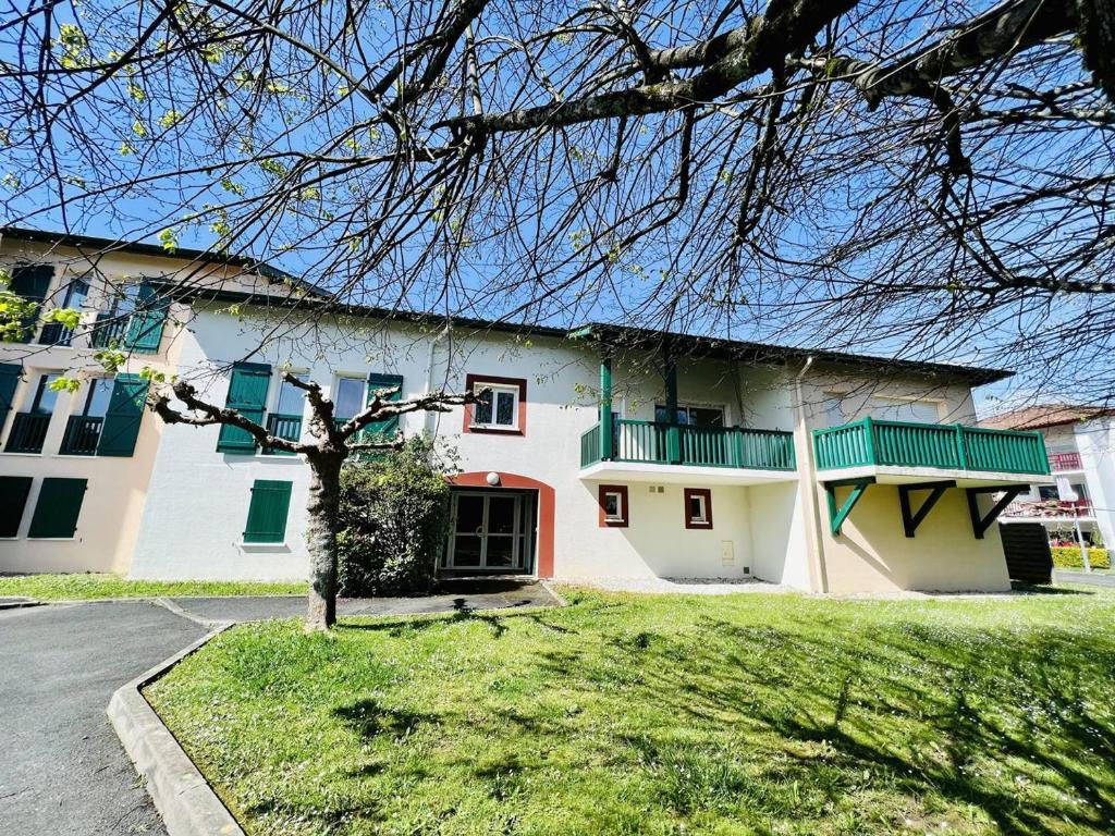 康博莱班Appartement Cambo-les-Bains, 2 pièces, 2 personnes - FR-1-495-46的白色的房子,设有绿色的窗户和庭院