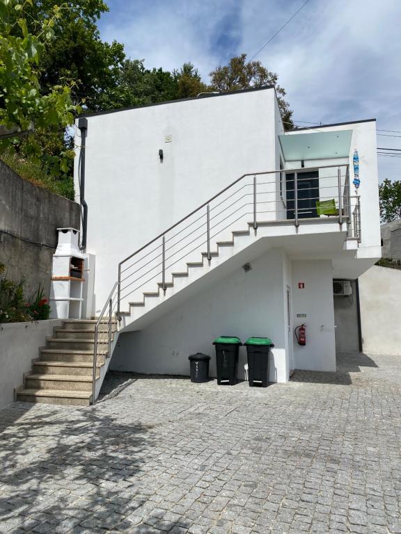 吉尔斯Cantinho Verde T1的白色的建筑,有楼梯和两个垃圾桶