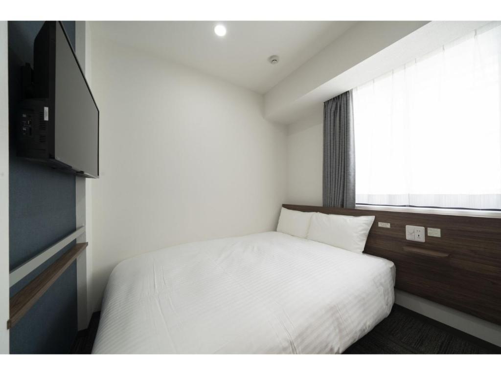 仙台R&B Hotel Sendai Higashiguchi - Vacation STAY 39923v的卧室配有白色的床和窗户。