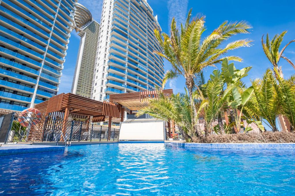 贝尼多姆Sunset Drive Resort Apartment 5-10 Poniente Beach的一座棕榈树和建筑游泳池