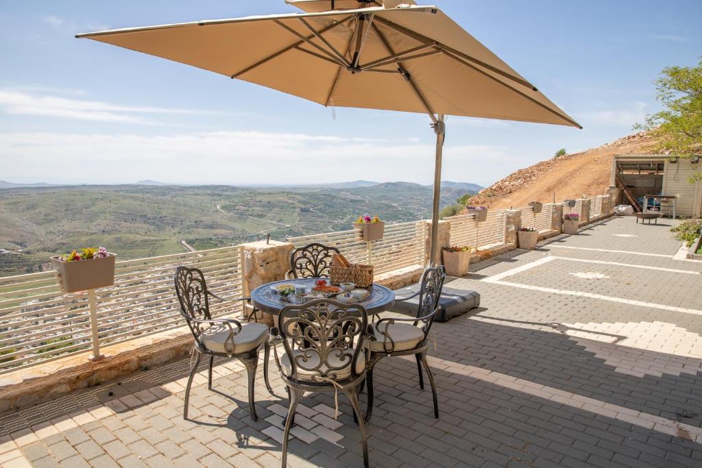 迈季代勒舍姆斯צימר ענאן בגולן的庭院配有桌椅和遮阳伞。