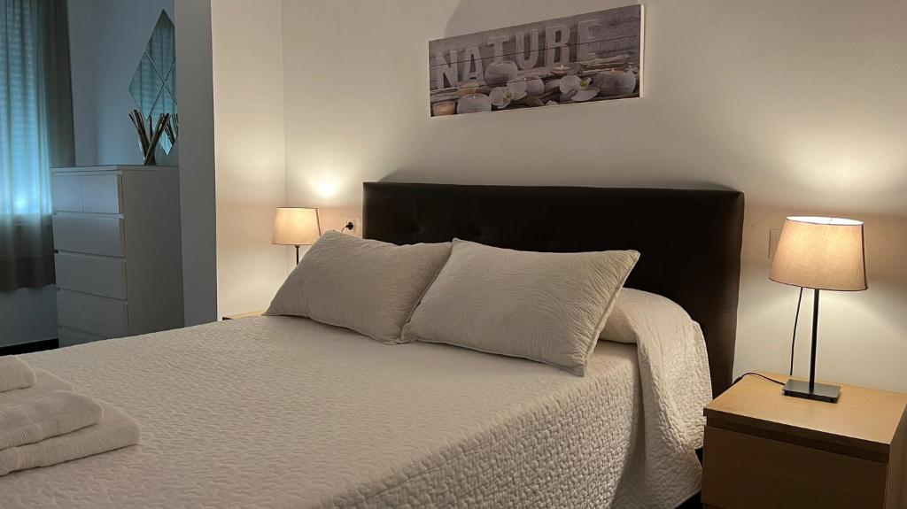 科尔多瓦Apartamento Puente Romano的一间卧室配有一张带白色床单和两盏灯的床。