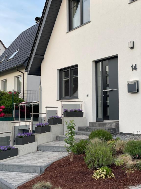 巴特萨尔茨乌夫伦OD Ferienwohnung的白色的房子,有黑色的窗户和紫色的鲜花