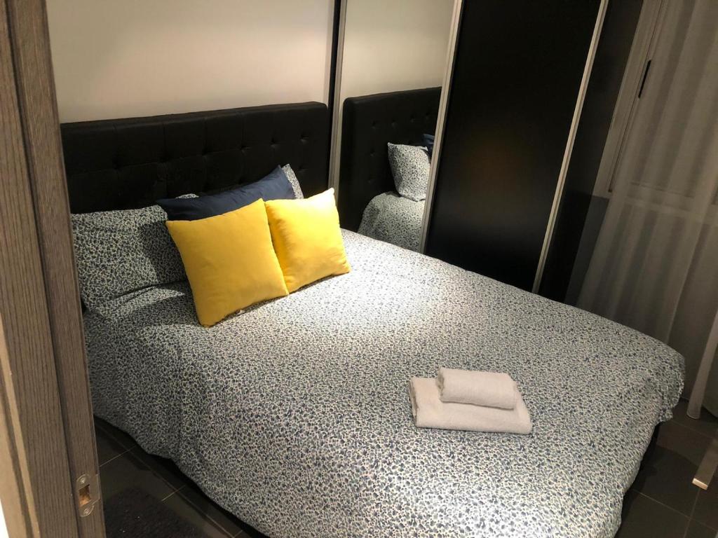 埃尔切Elche piso entero 3 dormitorios dobles的一张带黄色和蓝色枕头的床和镜子