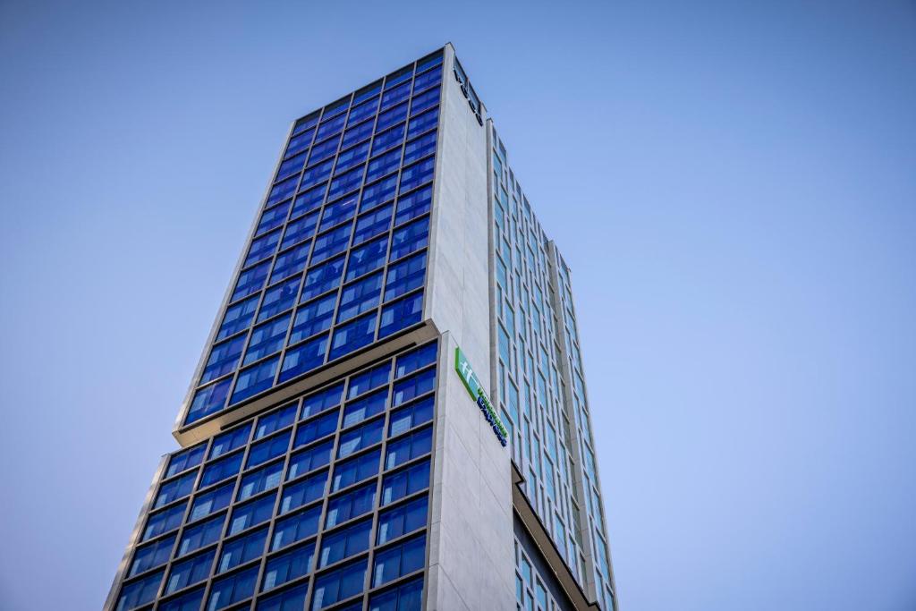 奥克兰Holiday Inn Express Auckland City Centre, an IHG Hotel的一座高大的建筑,上面有蓝色的窗户