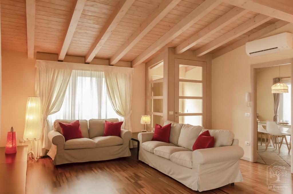 西尔米奥奈Appartamenti La Piazzetta的客厅配有2张白色沙发和红色枕头